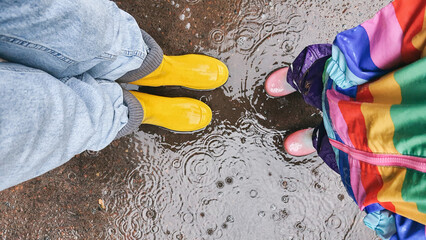 Mother and daughter together playing in puddle.