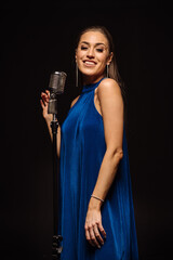 Stylish female singer performs a song into a retro microphone on stage