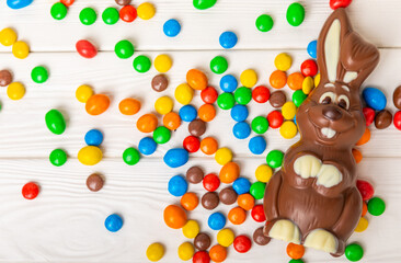 Easter chocolate bunny on a light texture table. Chocolate eggs and other sweets. Easter celebration concept. Easter sweets on the table. Place for text. copy space.