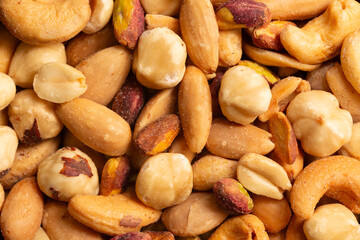 Mixed nuts close-up, top view. Roasted, peeled, salted peanuts, hazelnuts, cashews, almonds,...