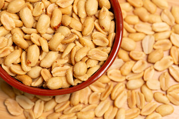 Salted peanuts in bowl in selective focus and out of focus. Peeled roasted peanuts close-up, top view.