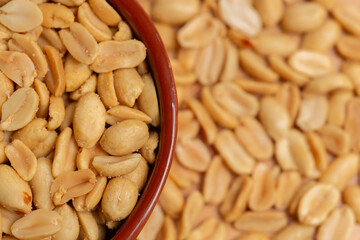 Peanuts in bowl in selective focus and out of focus, top view. Peeled salted roasted peanuts close-up.