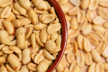 Peeled roasted peanuts close-up. Salted peanuts in bowl in selective focus and out of focus, top view.