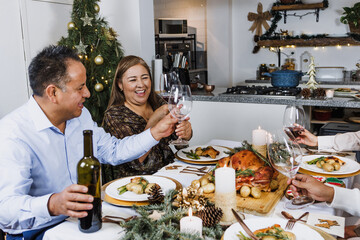 Latin family having Christmas dinner and making wine toast at home in Mexico Latin America,...
