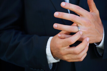 Man, groom and hands with ring for marriage, commitment or symbol of love, trust or care. Closeup of married male person in suit adjusting jewelry on finger for vow, promise or wedding engagement