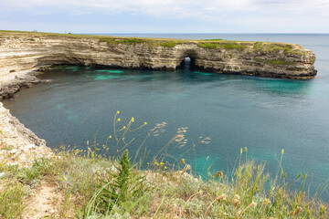 Fototapeta premium Cape Tarkhankut on the Crimean peninsula. The rocky coast of the Dzhangul Reserve in the Crimea. The Black Sea. Turquoise sea water. Rocks and grottoes of Cape Tarkhankut.