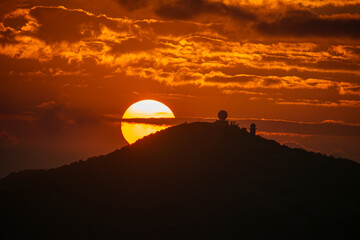 Obraz premium Orange-red sky, sunset and silhouettes of mountains. Wufenshan Weather Radar Station, Ruifang District, New Taipei City, Taiwan.