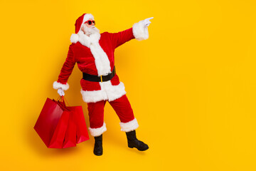 Full length photo of grandfather dressed red santa claus costume directing finger copyspace promo shop isolated on yellow color background