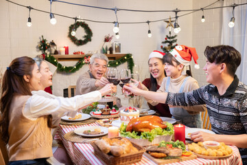 Asian family cheering and drinking red wine celebrating Christmas or New Year party