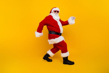 Fototapeta na wymiar Full size profile portrait of eccentric aged santa claus sneaky walking christmas time isolated on yellow color background