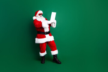 Full length photo of funky shocked claus wear red costume reading obedient children christmas list empty space isolated green color background