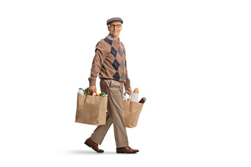 Full length shot of a pensioner with grocery bags walking and looking at camera