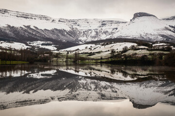 Snowy landscape on the reservoir with the reflection of the mountain