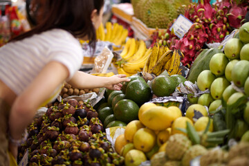 Girl reaching for avocado on market stall