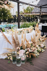 Wedding ceremony. Presidium for the newlyweds, decorated with candles and vases with white and pink natural flowers such as eustoma, roses and reed. Floristic concept 