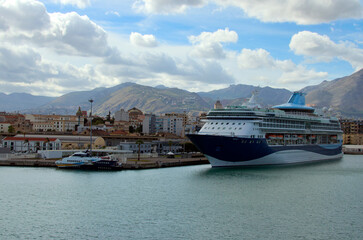 Panoramic landscape view of harbor in Palermo with moored luxury cruise liner. Cityscape and mountain range in the background. Colorful vibrant sky. Travel and tourism concept
