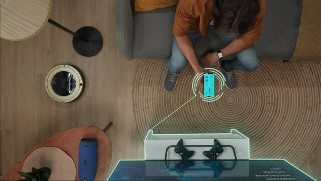 Top view of man sitting on the sofa, switching on tv, cleaner, lights and music speaker using app on smartphone. Infographic digital image on objects.
