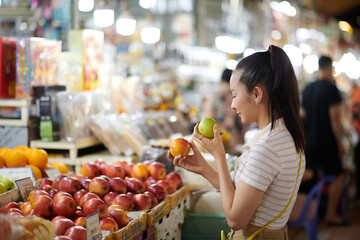 Smiling young woman buying organic fruits at local market
