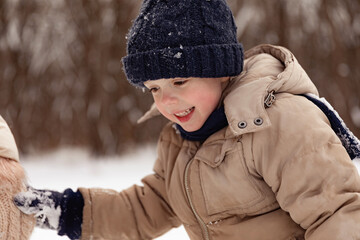Little boy holding his mother's hand, walking on the street in winter, warm clothing. Happy winter time outdoor