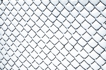 A mesh fence covered with freshly fallen clean snow,.