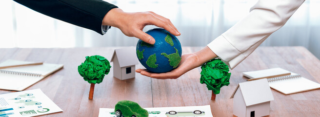 Business people holding paper earth together over office table. Green corporate company...