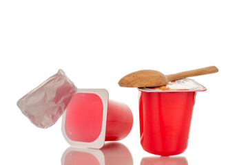 One fruit yogurt with a spoon in a plastic container and one empty container, close-up, isolated on white.