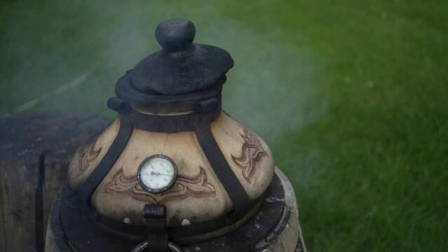 Close up smoke from modern ceramic wood-fired tandoor in outdoor kitchen. 