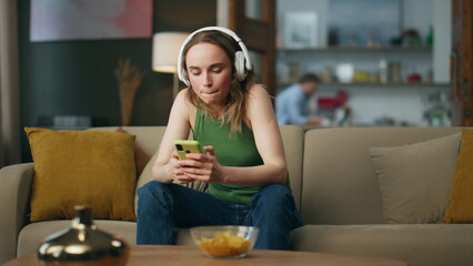 Relaxed girl listening headphones music sofa interior. Lady moving in song beat