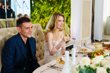 Happy bride and groom at banquet table in restaurant. 