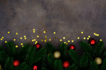 Christmas background with fir branches, christmas red toes, gold stars on brown background. Top...
