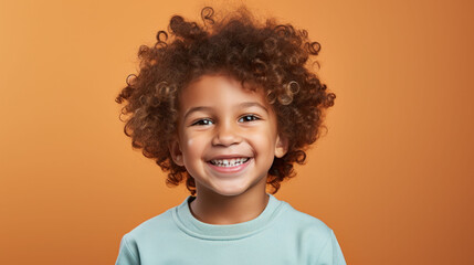 Portrait of a smiling child with curly hair against a warm background, illustrating oral health and joy. - obrazy, fototapety, plakaty