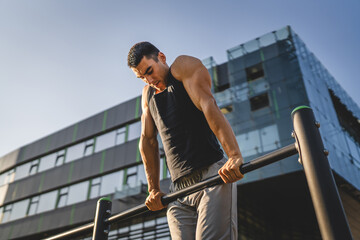 One man muscular male athlete training pull ups outdoor in sunny day