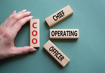COO - Chief Operating Officer symbol. Concept word COO on wooden blocks. Businessman hand....