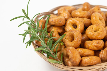 Traditional italian snacks taralli or tarallini with rosemary in a wicker plate isolated