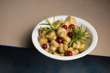 Small champignon mushrooms stewed in sour cream with rosemary and cranberries