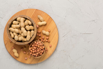 Peeled and unpeeled peanuts on concrete background, top view