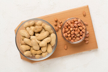 Peeled and unpeeled peanuts on concrete background, top view