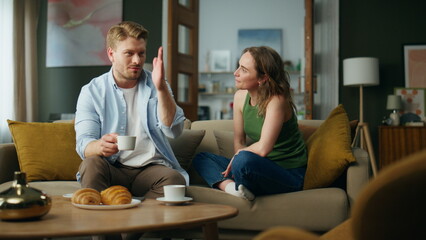 Chilling spouses drinking tea at sofa interior. Couple enjoying coffee talking
