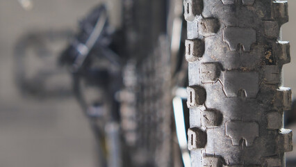 An old cracked mountain bike tyre. Close-up. A studded wheel of a mtb bicycle. Blurred transmission...