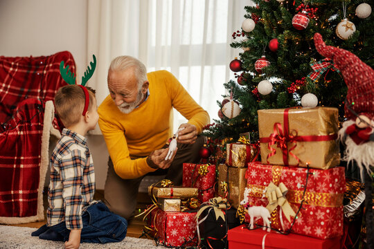 A happy grandfather is showing christmas decoration near christmas tree on christmas and new year.