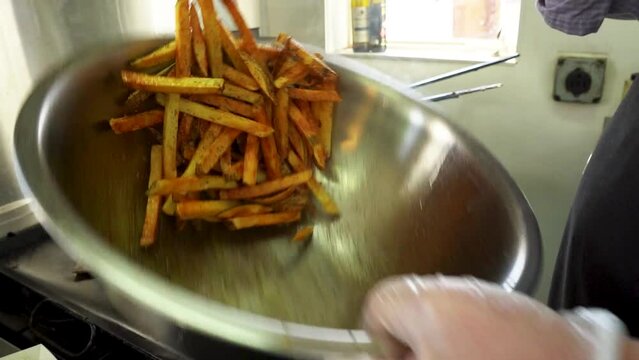 Fresh french fries being seasoned