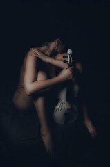 Fototapeta na wymiar Nude girl with a beautiful body in the twilight with a white violin