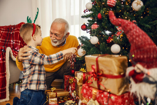 A grandson and grandfather are playing with christmas ornaments on christmas and new year at home.
