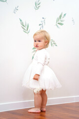 Cute little girl in a fluffy white dress at home