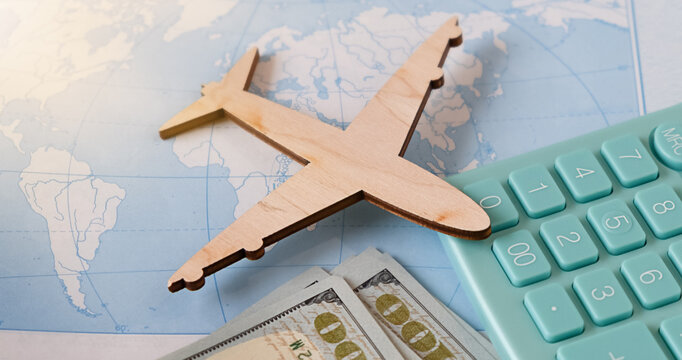 Calculation of the cost of rest or emigration, air flight. Travel background. Traveler, tourist accessories, toy airplane, calculator on map background. Top view.