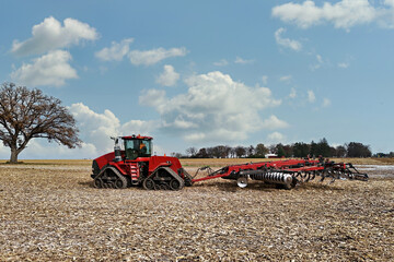 Large red tracked tractor getting ready to cultivate a field with a chisel plough