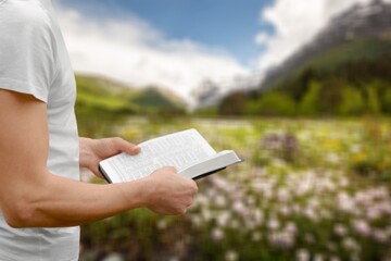 Person reading book praying with Bible