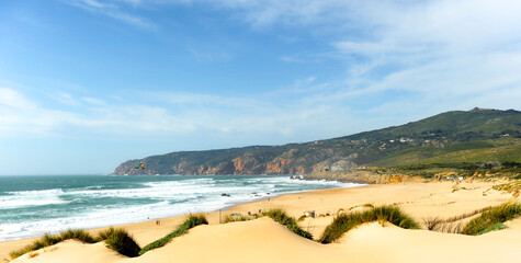 Praia do Guincho beach scenic view with Cresmina Dunes in foreground near Cascais, Portugal. Famous spot on the Portuguese coast of the Atlantic Ocean for surfing, windsurfing and kitesurfing