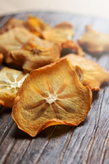 Persimmon chips close-up on a wooden table.