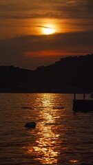 Vertical shot of sunset sun shining through the clouds and reflecting in sea waves. Holiday, summer vacation and tourism